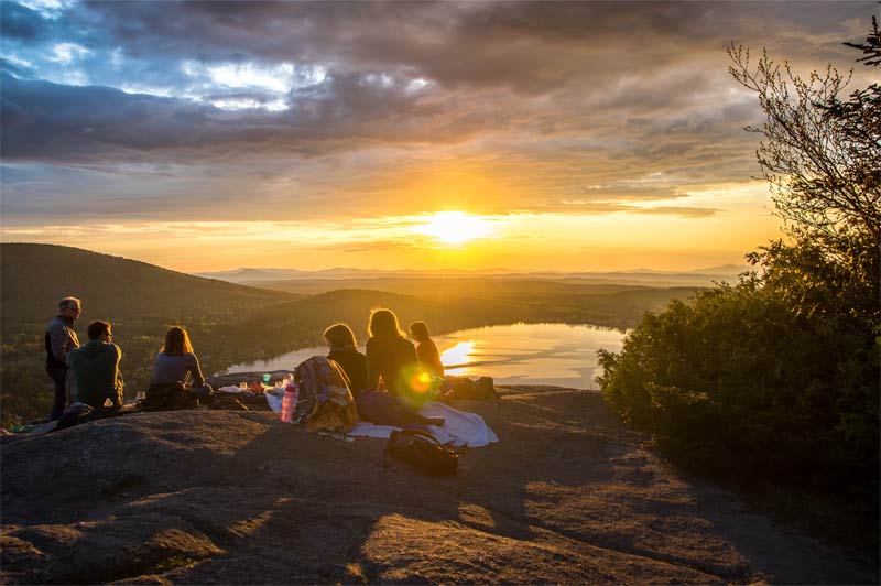 group of people watching sunset over lake