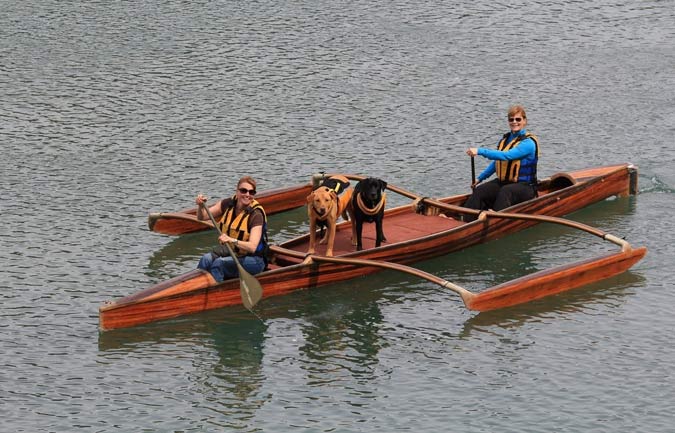Dogs and their owners enjoy a ride aboard a canine coaster outrigger canoe
