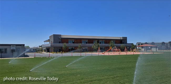 playground and field view including 2-story campus building